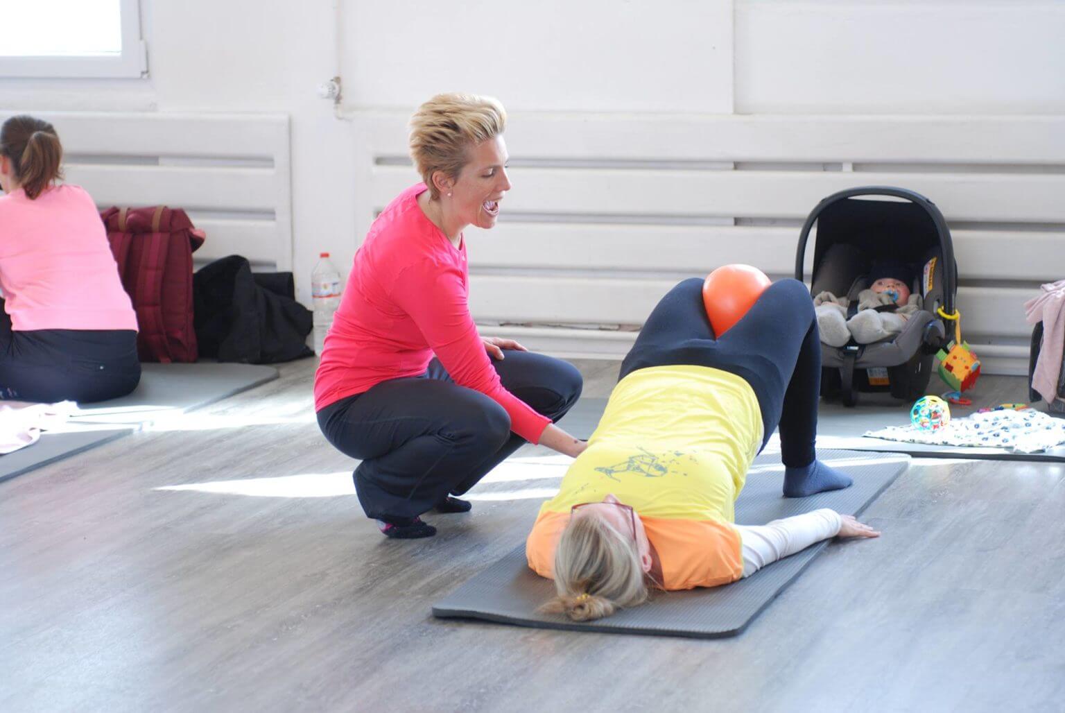 buggyFit Trainerin begleitet eine Mama bei einer sanften Rückbildungsübung, Baby daneben