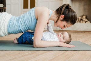 Side view of woman doing plank exercise and spending time with her son at home