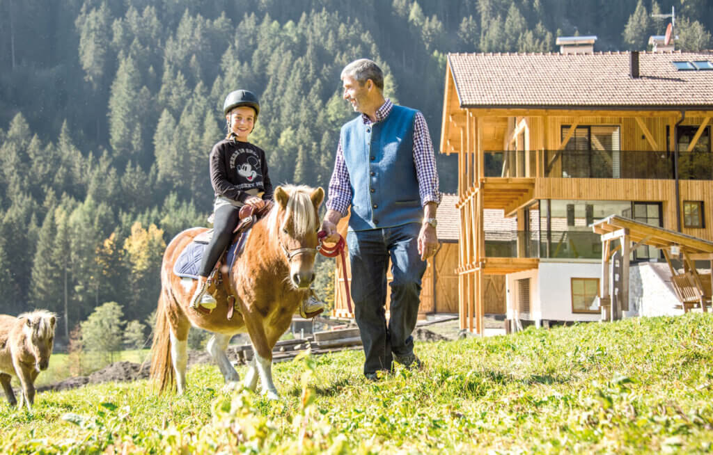 Ein Mädchen beim reiten, wird von einen Mann geführt.