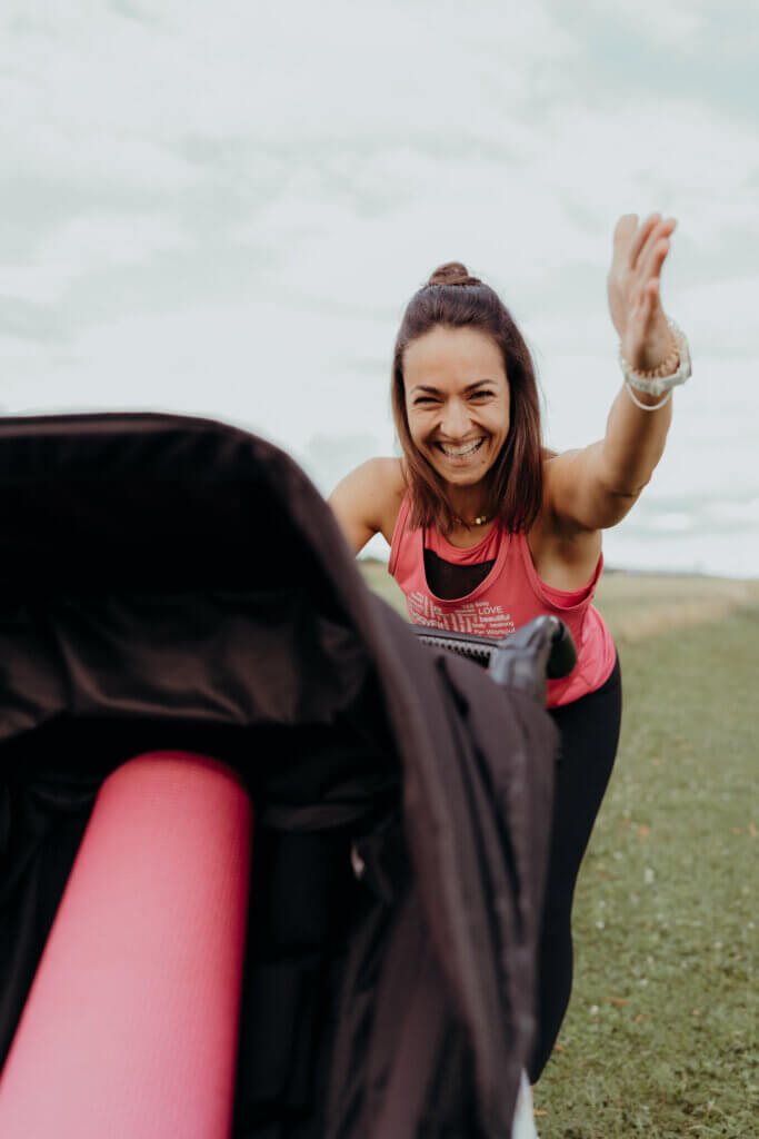 Lächelnde Mama, bei einer Übung am Kinderwagen.